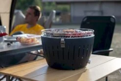 LotusGrill XL Hybrid Houtskoolbarbecue - Rood -Winkel Voor Kampeerartikelen lotusgrill in gebruik met toppy shirtje 2